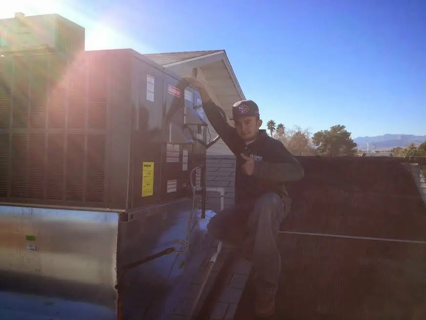HVAC technician performing AC Tune-Up on a rooftop unit in Bloomington